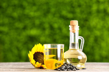 Jug and glass of sunflower oil on table outdoors