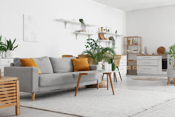 Interior of cozy dining room with houseplants, table and sofa