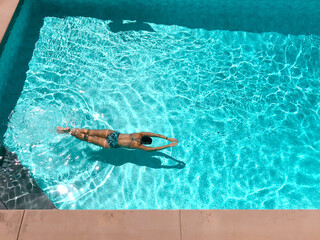High angle view of a woman swimming face down in backyard swimming pool on a sunny day