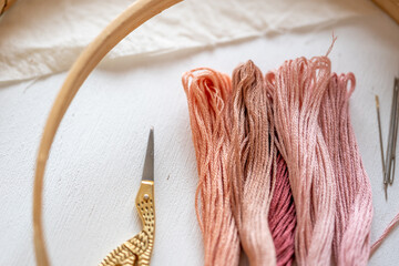 primer plano de tijeras para bordado de cigüeña, madejas de hilo para bordar en colores rosa con...