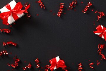 Red party streamers, gift boxes and confetti on black background. Banner mockup for Black Friday, Birthday, Valentines Da, Anniversary.