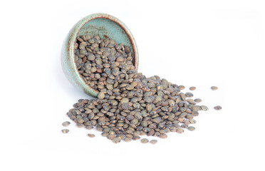 French Green or Puy Lentils Spilling from a Green Pottery Bowl Isolated on White