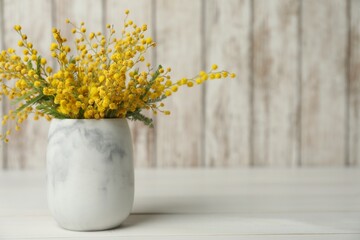 Bouquet of beautiful mimosa flowers on white wooden table. Space for text