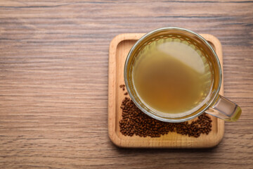 Cup of aromatic buckwheat tea and granules on wooden table, top view. Space for text