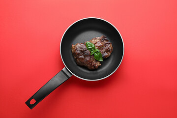 Tasty fried steak in pan on red background, top view