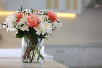 Vase with beautiful flowers on countertop in kitchen, space for text. Interior design