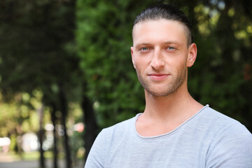 Portrait of handsome young man in park, space for text