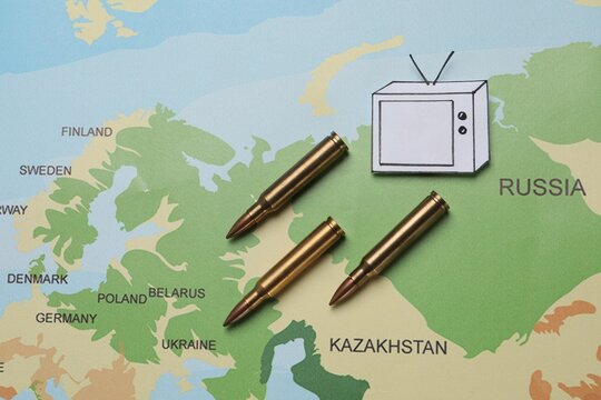 Paper TV And Bullets On World Map, Flat Lay. Hybrid Warfare Concept