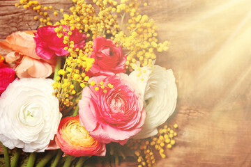 Beautiful ranunculus and mimosa flowers on wooden background