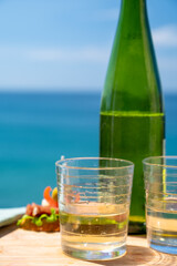 Txakoli or chacolí slightly sparkling very dry white wine produced in the Spanish Basque Country, served outdoor with view on Bay of Biscay, Atlantic Ocean.