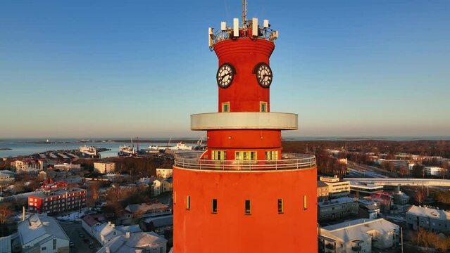 Aerial view closely around the water tower, revealing the cityscape of Hanko, sunset in Uusimaa, Finland - rotating, drone shot
