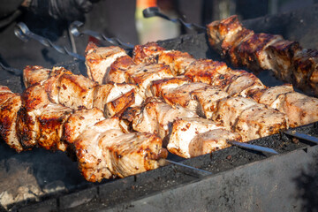 Marinated shashlik also known as shish kebab is grilled on a charcoal grill. Pork pieces on steel skewers. Street food in a public place