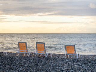 Empty sunbeds on the beach. Seaside chairs. End of beach season. At sunset. Vacation at the resort.