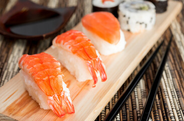 Sushi Set nigiri shrimp and salmon and sushi california rolls with avocado and maki with carrot, on wood,top view, soy sauce