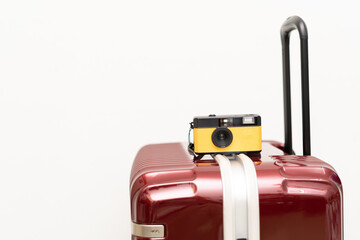 Travel Concept vintage camera on red luggage gray background, with copy space. Suitcase and retro film camera travel concept.