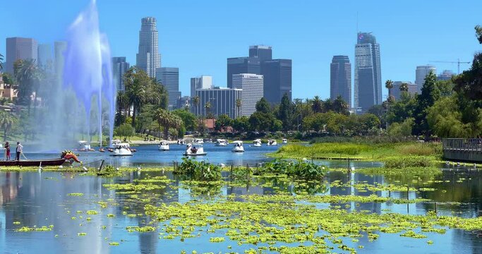 Tourists in boats at Echo Park Lake near Los Angeles downtown financial and business district skyline and skyscrapers, California, 4K