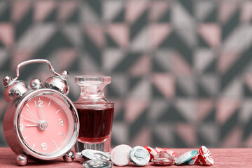 Pink toned bed table with fancy clocks and perfume for girl. Perfume and women accessories