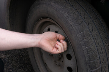 The hand twists or unscrews the nipple cap from the car wheel. - obrazy, fototapety, plakaty