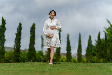 happy pregnant woman walking in park