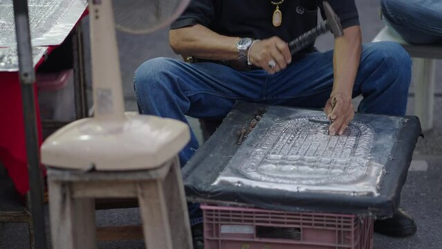 A close up of senior sculptor hands working on his sculpture in the market with hammer and chisel