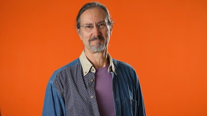 Fototapeta premium Happy bearded man 50s look camera smiling isolated on sold orange background studio portrait. People emotions lifestyle concept
