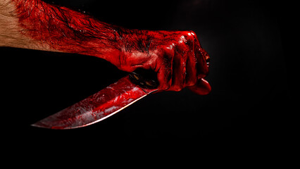 Man holding knife with bloody hand on black background. 