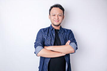 Fototapeta premium Portrait of a confident smiling Asian man standing with arms folded and looking at the camera isolated over white background