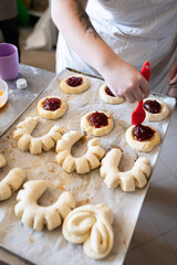 The process of making sweet pastries and filling dough blanks with jam. Vertical photo.