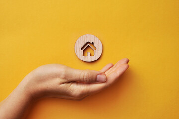 A wooden house in the hands of a man. A symbol of protection and care for home and family