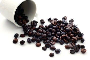 Coffee beans outpour a cup on a white background