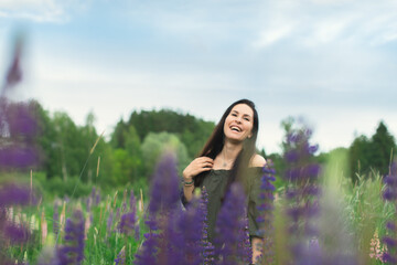 An attractive woman in a field with a summer bouquet of wildflowers Lupinus. Front view.