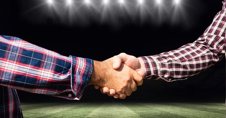 Composition of two businessmen shaking hands over sports stadium