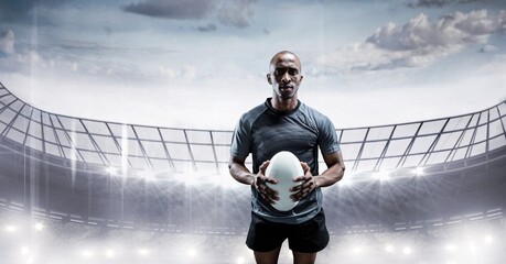 Composition of male rugby player holding rugby ball over sports stadium