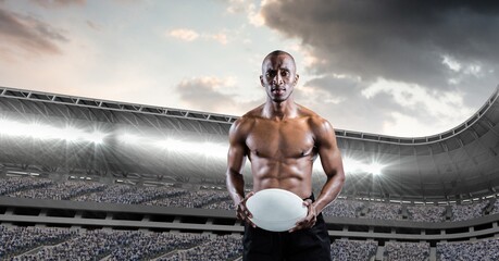 Composition of shirtless male rugby player holding rugby ball over sports stadium