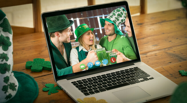 Happy caucasian friends in hats making st patrick's day video call smiling on laptop screen at home