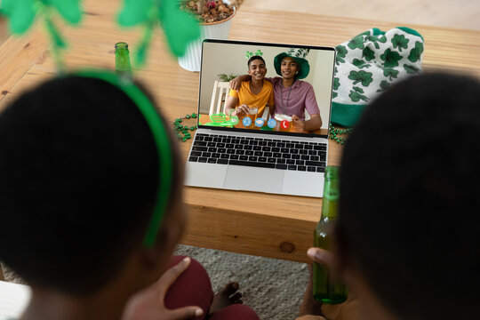 African american couple making st patrick's day video call to smiling friends on laptop at home