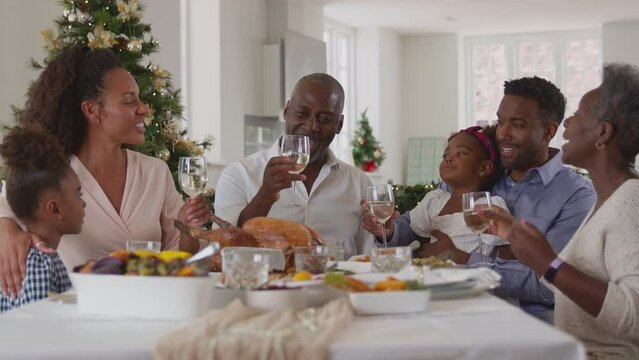 Multi-generation family celebrating Christmas at home making a toast before eating meal together - shot in slow motion
