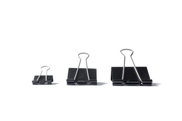 Three black binder clips of various sizes used to staple documents against
