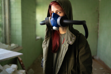 Post apocalypse concept. A woman in a gas mask walks in an abandoned building among the ruins....