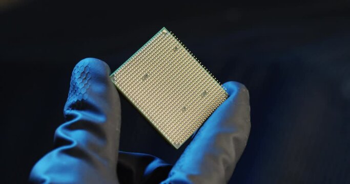 Close-up shot of gloved hand holding piece of Microchip.
