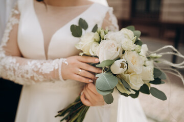 Beautiful bride holds white bouquet. bouquet from white rosses in woman's hands