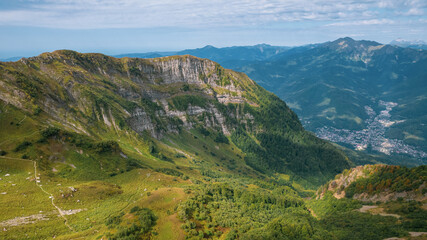 Naklejka premium Alpine Meadows Trail, Krasnaya Polyana Resort. Alpine Meadows Walking Route. Aerial view of the green mountain valley, surrounded by high mountains.