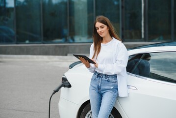 girl charging electro car at the electric gas station