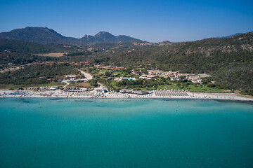 Obraz premium Sardinia panorama clear water aerial view. Sardinia famous beaches white sand clear turquoise water aerial view. The beaches of Sardinia in the background mountains cumulus clouds top view.