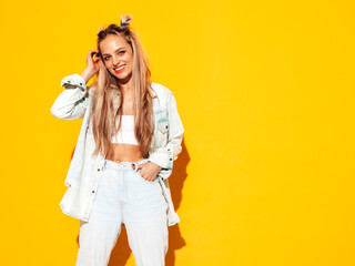 Portrait of young beautiful smiling blond female in trendy summer clothes. carefree woman posing near yellow wall in studio. Positive model having fun indoors. Cheerful and happy