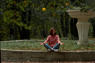 A woman in Casual clothes does yoga in an old park