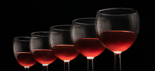 glasses with red wine on a black background, long layout elegant alcoholic beverages