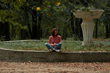 A woman in Casual clothes does yoga in an old park