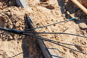 The high voltage electrical cable is laid in a trench under existing engineering sewerage networks. Laying a high voltage cable for supplying buildings with electricity.