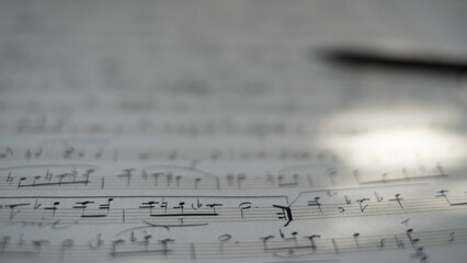 Background of musical notes: score for piano, close-up. Sheet with music notes and pencil